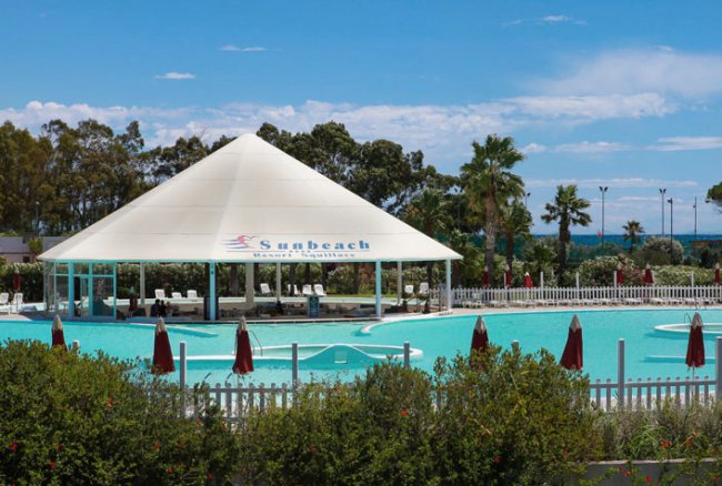 Piscina con gazebo bianco e ombrelloni rossi.
