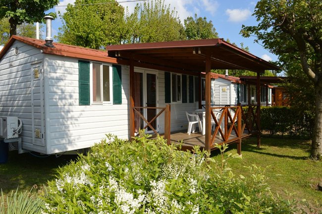 Esterno di bungalow bianco con veranda in legno.