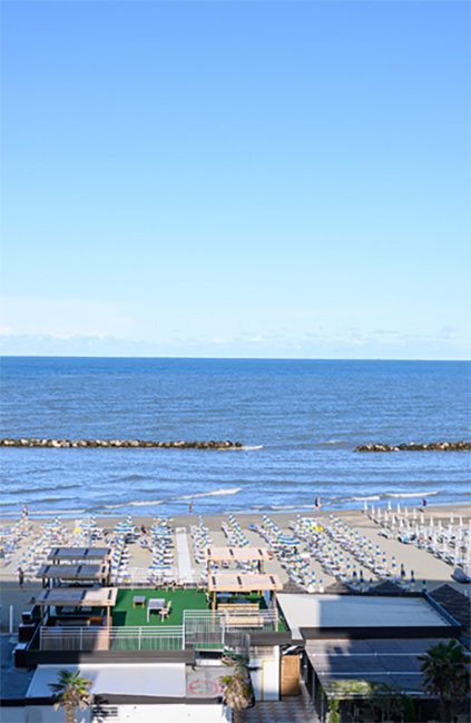 Spiaggia con lettini e mare in lontananza.