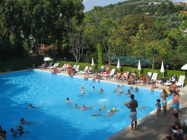 Persone giocano in una piscina affollata.