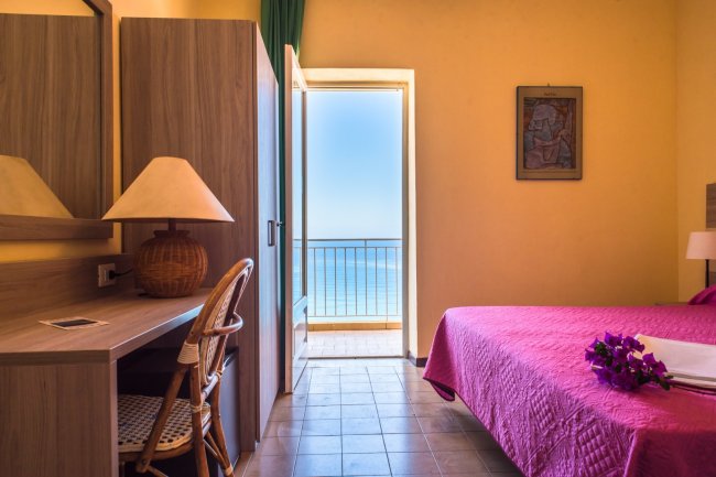 Camera con letto rosa e balcone vista mare.