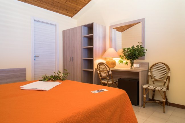 Camera d'albergo con letto arancione e scrivania.