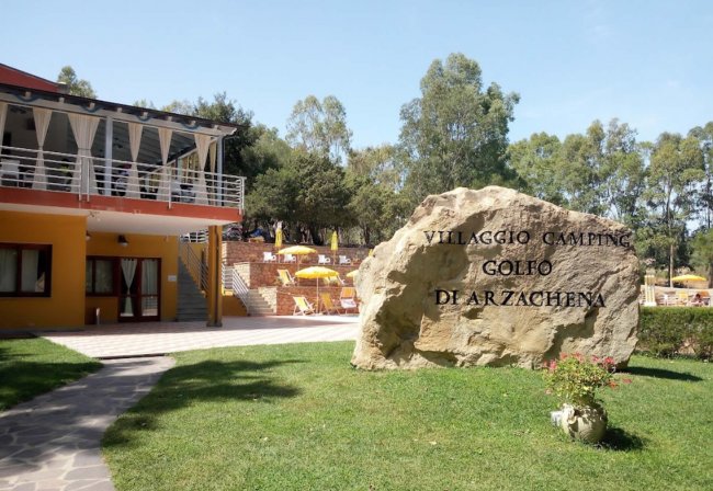 Entrata villaggio camping con insegna su roccia.