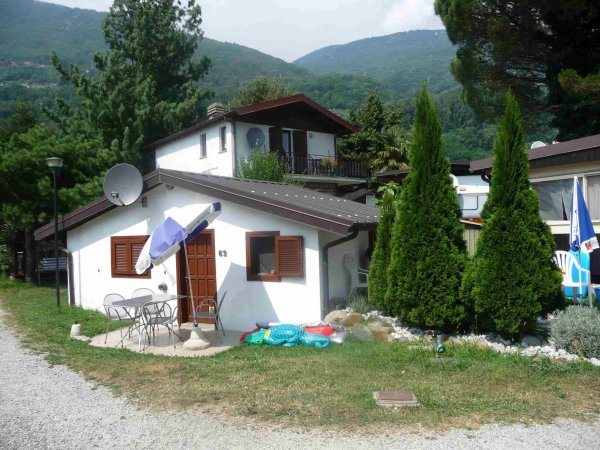 Casetta bianca con tavolo e ombrellone davanti.