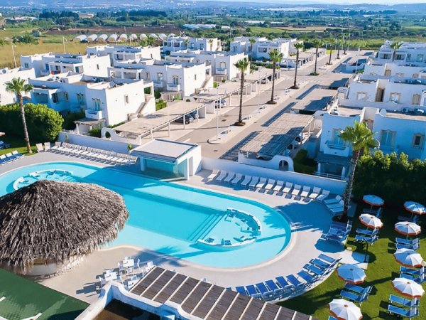 Complesso residenziale con piscina e ombrelloni.