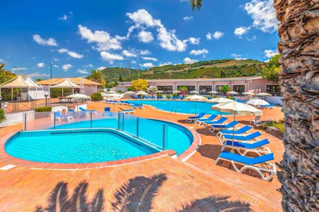 Piscine blu con lettini e ombrelloni sotto un cielo sereno.