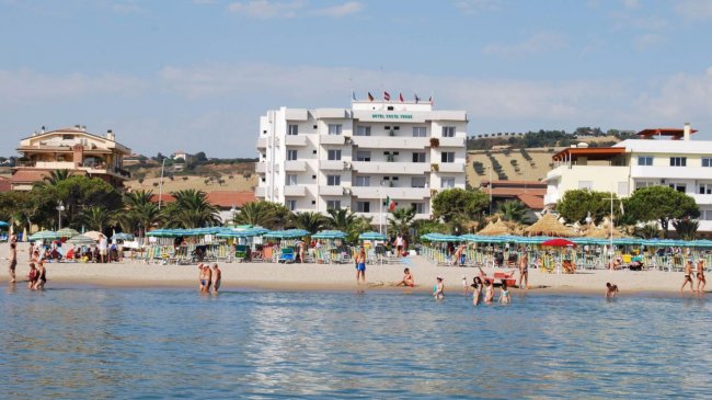 Edificio bianco fronte mare con spiaggia.