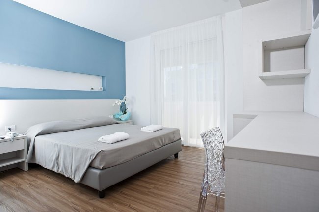 Stanza moderna con letto matrimoniale e pareti azzurre.