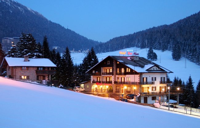 Hotel di montagna in un paesaggio innevato al tramonto.