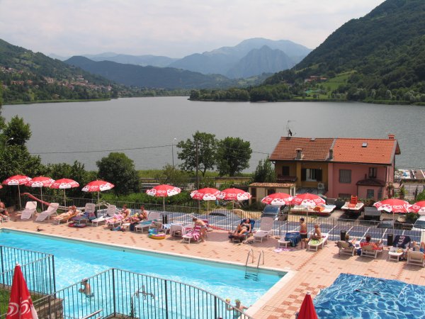 Piscina e lettini con vista lago e monti.