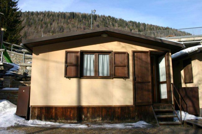 Casetta di legno su sfondo nebbioso e montano.
