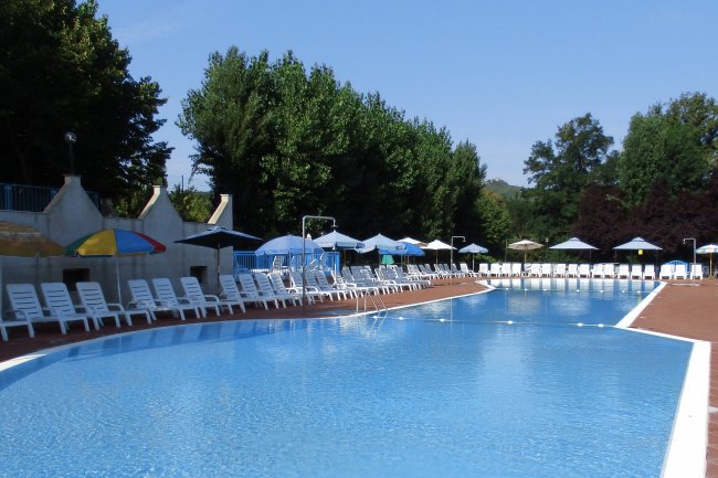 Grande piscina all'aperto con lettini e ombrelloni.