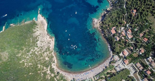 Vista aerea di una baia con spiaggia e barche.