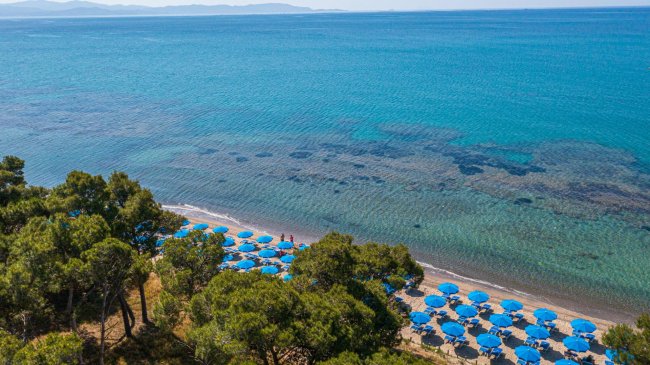 Spiaggia con ombrelloni blu e mare turchese.
