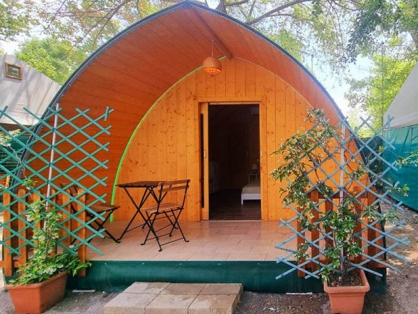 Una cabina in legno con tetto curvo, piccolo terrazzo e tavolino.