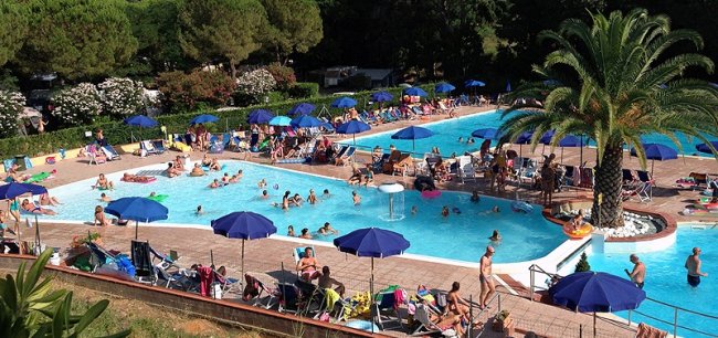 Piscina affollata con ombrelloni blu.