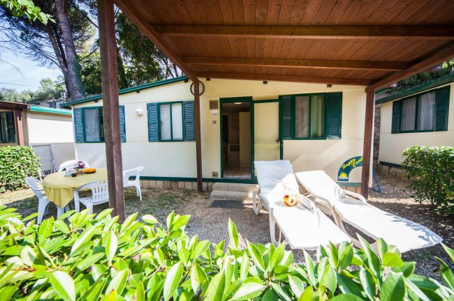 Bungalow con veranda, tavolo e sdraio all'esterno.