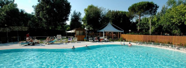 Piscina all’aperto con persone e lettini.