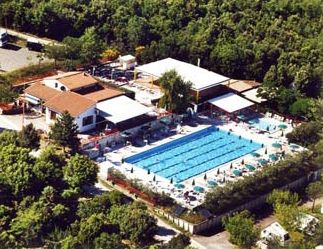 Vista dall'alto di un complesso con piscine e edifici circondati da alberi.