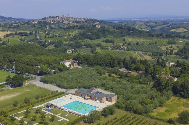 Vista aerea di una piscina e colline verdi sullo sfondo.