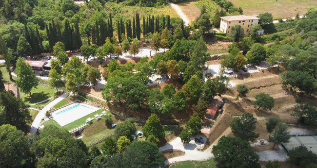 Vista aerea di una struttura immersa nel verde, con piscina e vialetti.