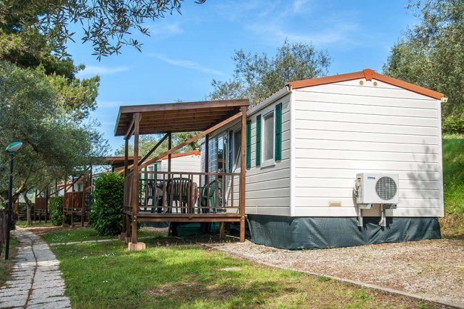 Una casa mobile bianca con veranda in un prato.