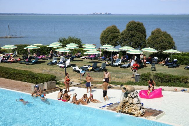 Piscina affollata vicino al mare con sedie a sdraio.