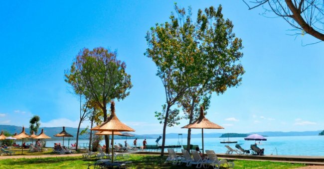 Lettini e ombrelloni vicino a un lago.