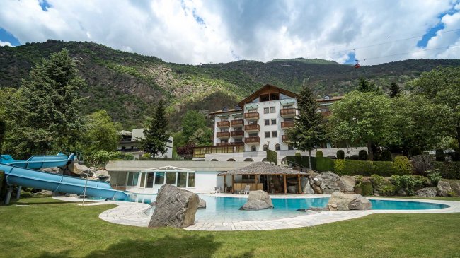 Piscina e hotel con montagne sullo sfondo.