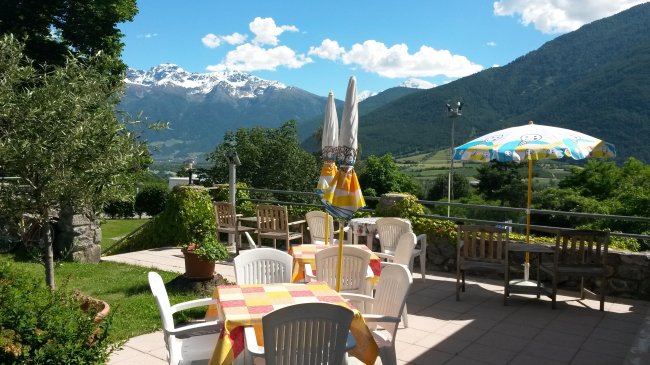 Terrazza con tavoli e vista monti innevati.