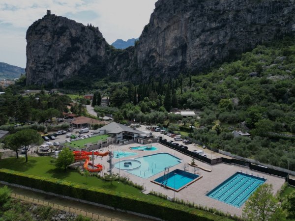 Piscina con scivoli, circondata da montagna e vegetazione.