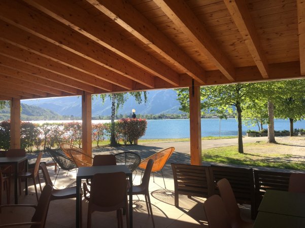 Veranda con sedie, tavoli e vista sul lago.