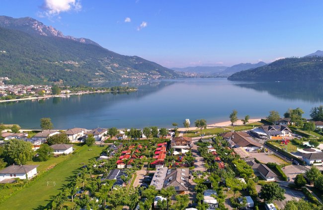 Vista aerea di un lago circondato da colline e case.