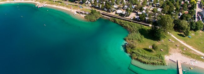Spiaggia e acqua turchese con cespugli verdi.