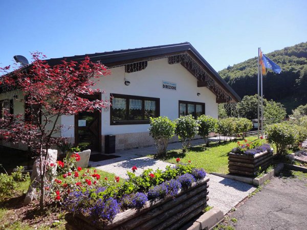Edificio bianco con giardino fiorito, segnalato come direzione.