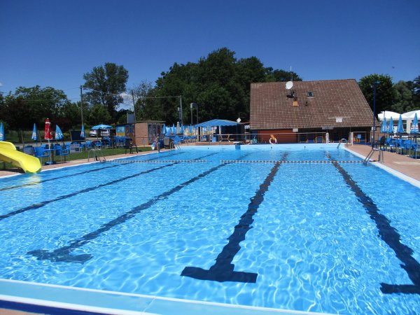 Piscina all'aperto con linee di nuoto e scivolo giallo.