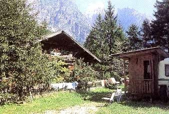 Chalet in montagna circondato da alberi e prato verde.