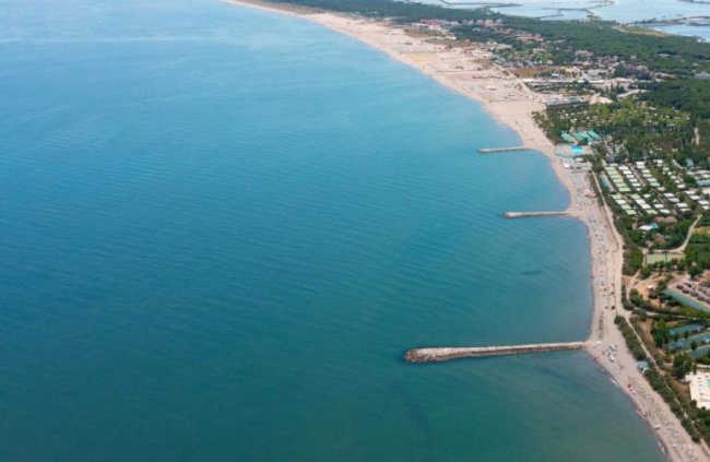 Spiaggia lunga vista dall'alto con mare blu.