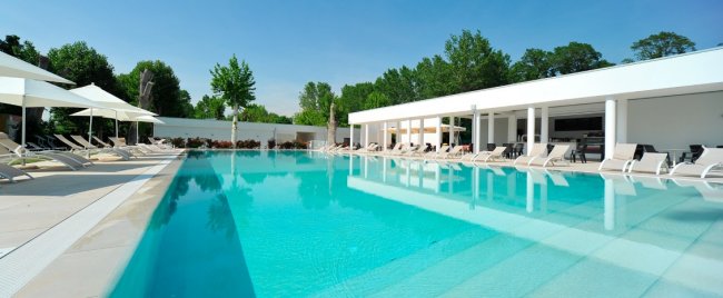 Ampia piscina all'aperto con sdraio e ombrelloni.