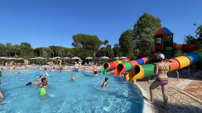 Piscina con scivoli colorati e persone che nuotano.