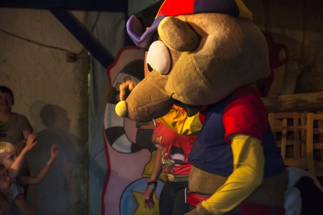 Uomo in costume da mascotte animale durante un'esibizione per bambini.
