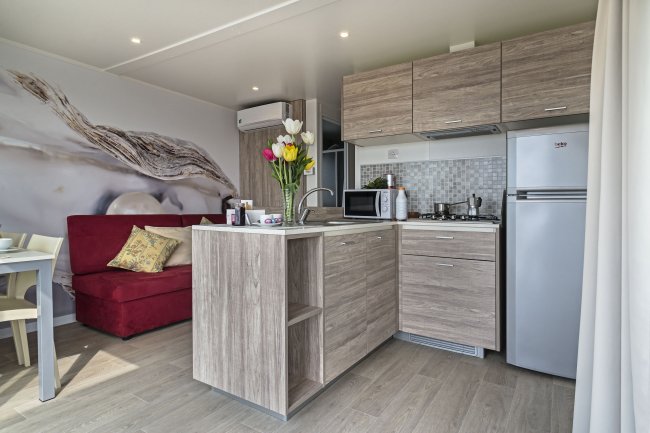 Interno di una cucina moderna con mobili in legno e un divano rosso.