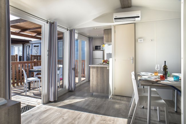 Interno moderno con cucina e sala da pranzo, accesso a terrazza esterna.