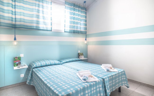 Camera con due letti, arredamento azzurro a righe.
