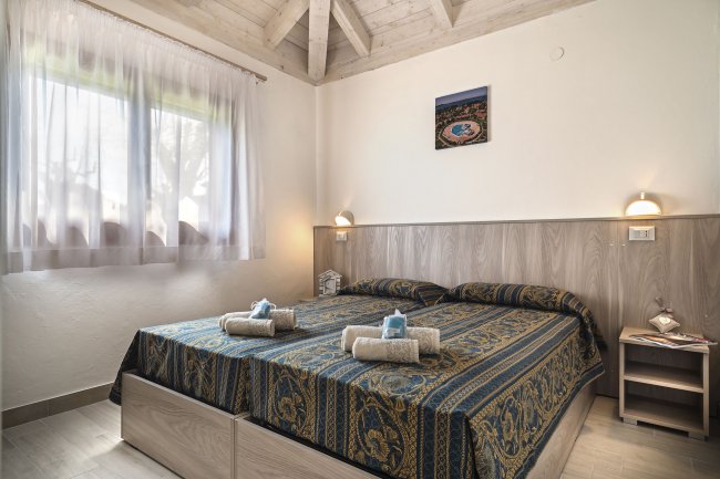 Camera da letto con letto matrimoniale, copriletto decorato e soffitto con travi a vista.