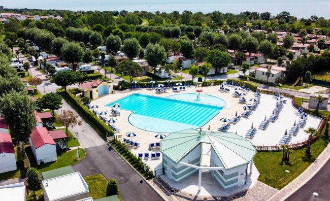 Grande piscina circondata da sdraio e ombrelloni.