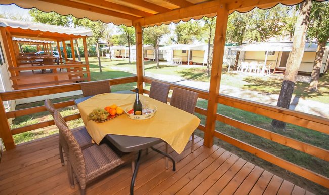 Veranda in legno con tavolo apparecchiato.
