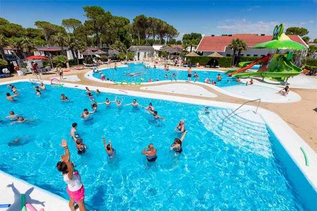 Piscina con persone che nuotano e un grande scivolo.