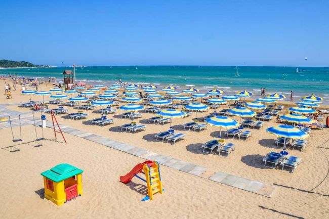Spiaggia con ombrelloni e lettini blu e gialli.