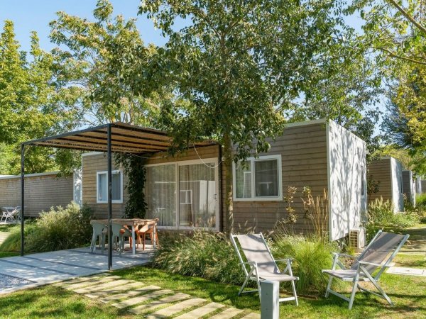 Bungalow immerso nel verde con sdraio e tavolo esterno.